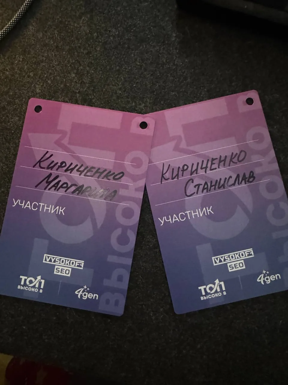 Два бейджа участников конференции «Высоко в ТОП!» с рукописными фамилиями и логотипами Vysokoff SEO и 4gen