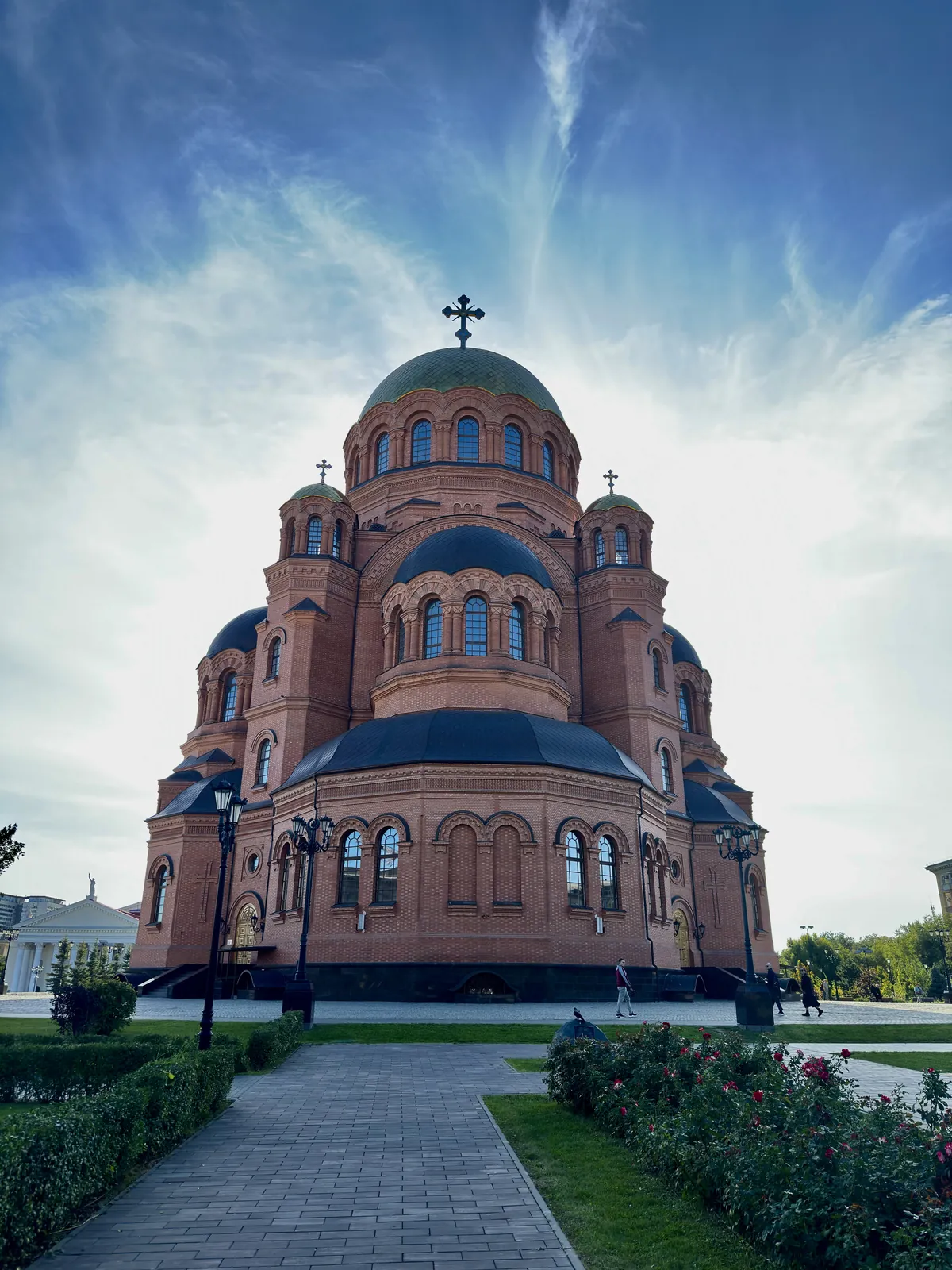 Кирпичный собор с зелёными куполами на фоне неба с облаками